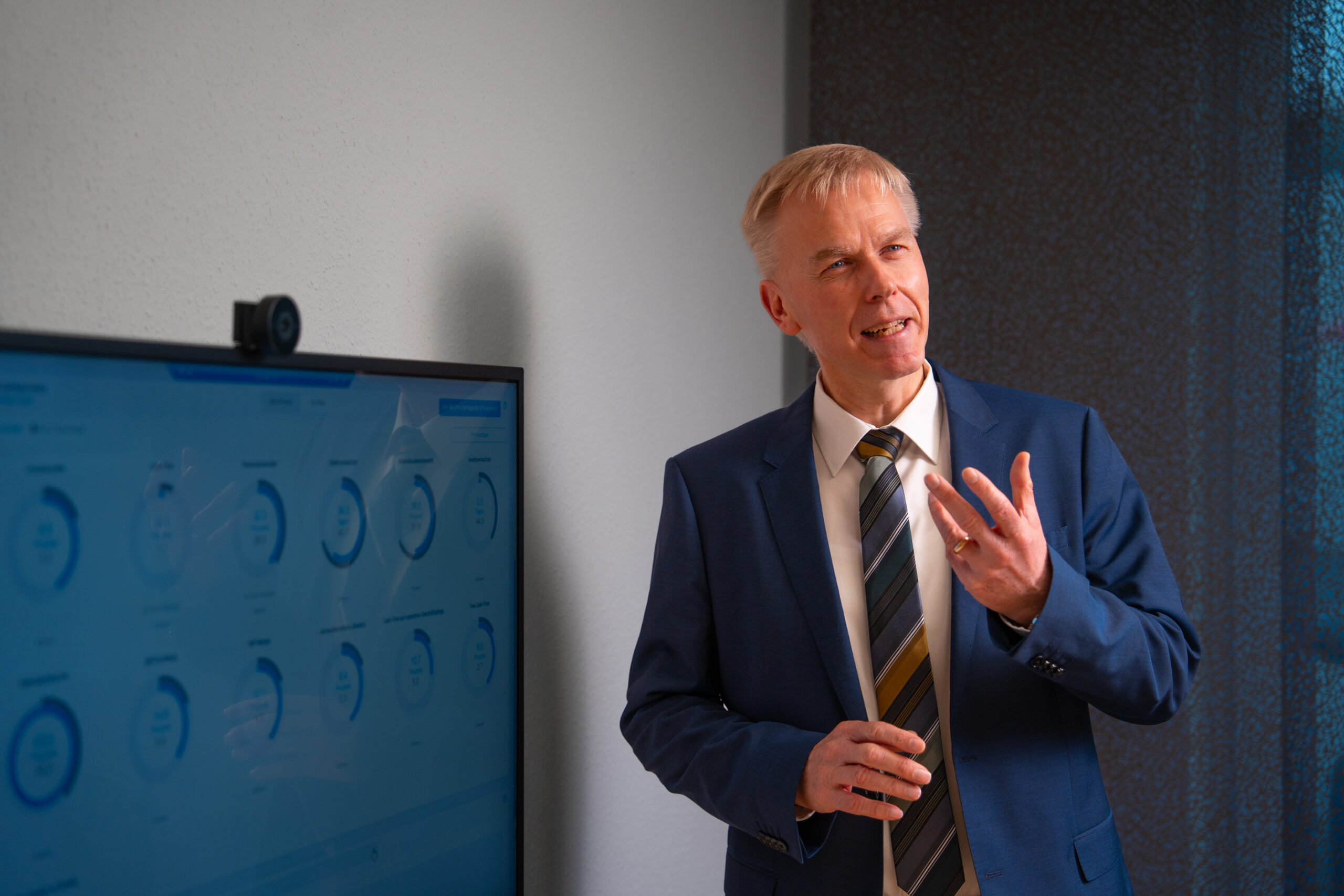 Steuerberater erklärt einem Mandanten am Tisch Finanzdaten auf einem Tablet während eines persönlichen Beratungsgesprächs.