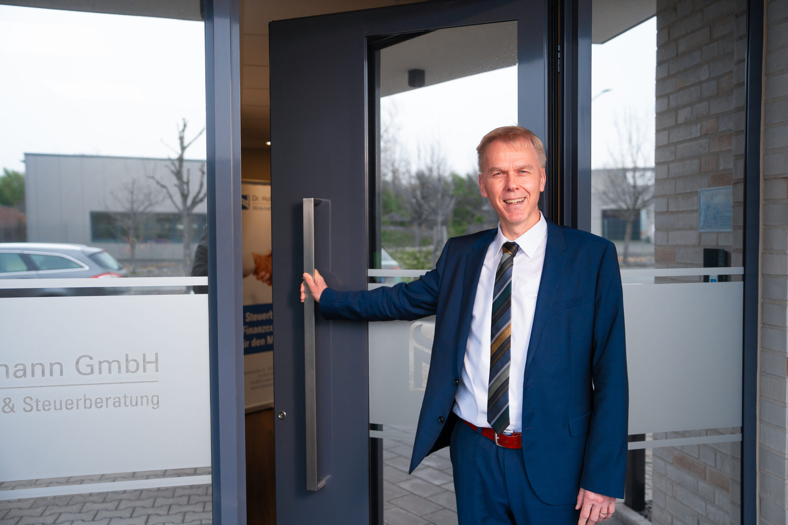 Steuerberater Sebastian Hollmann begrüßt Mandanten am Eingang der Steuerkanzlei in Rheda-Wiedenbrück.