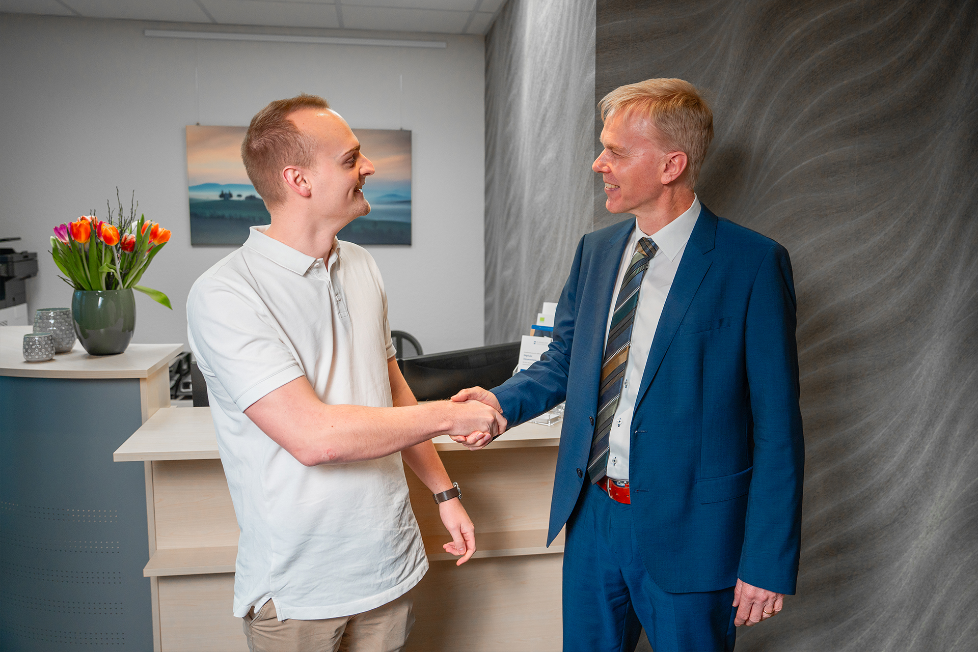 Sebastian Hollmann begrüßt Mandanten per Handschlag in der Kanzlei der Steuerberatung in Rheda-Wiedenbrück.
